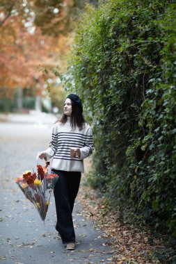 Sonbahar parkında şemsiyesi olan bereli güzel bir genç kız. Sonbahar