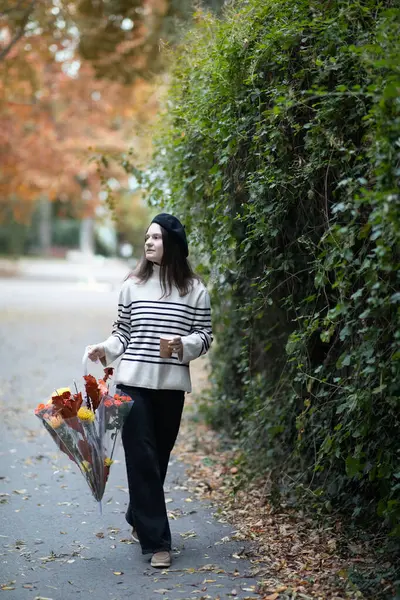 Sonbahar parkında şemsiyesi olan bereli güzel bir genç kız. Sonbahar