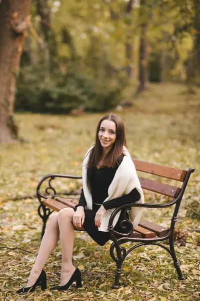 Güz parkında siyah kısa elbiseli güzel bir genç kız. Sonbahar