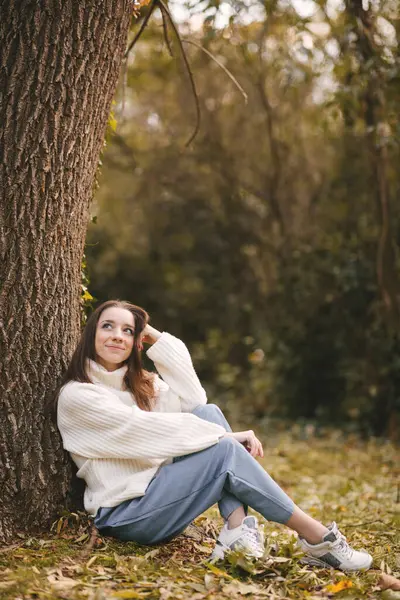 Sonbahar parkında beyaz kazaklı güzel bir genç kız. Sonbahar