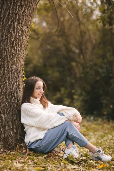 Sonbahar parkında beyaz kazaklı güzel bir genç kız. Sonbahar