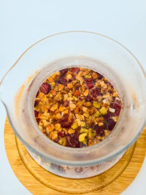 Beyaz zemin üzerinde ahşap bir standın üzerinde meyveli sonbahar çayı ile şeffaf çaydanlık. Sonbahar. Sonbahar havası. konfor