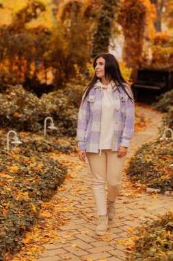 Sonbahar parkında kareli ceketli güzel esmer kız. Sonbahar konsepti. Sonbahar havası. sonbahar