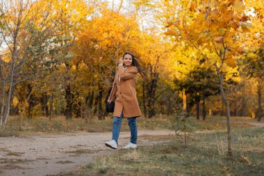 Güz parkında kahverengi ceketli güzel mutlu genç kız. Sonbahar günü. Sonbahar sezonu. sonbahar