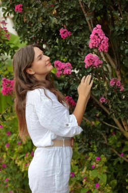 Pembe çiçekli bir ağacın yanında güzel bir genç kız. Yaz konsepti