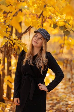 Siyah elbiseli genç bir kadın ve sonbahar parkında siyah bir şapka. Sonbahar sezonu. Sonbahar havası. sonbahar. 