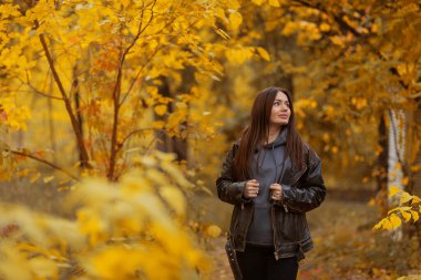 Sonbahar parkında yürüyen bej ceketli güzel, mutlu esmer kız. Sonbahar konsepti. Sonbahar sezonu. sonbahar.