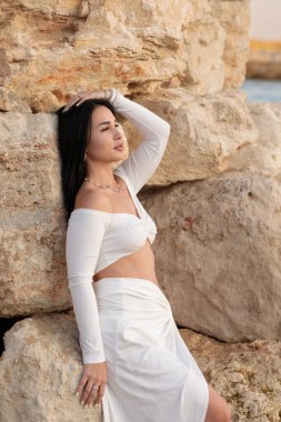 Yazın kumsalda denizde beyaz elbiseli güzel esmer kız. Yaz konsepti.