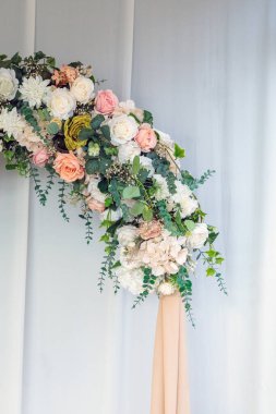 Allık, krem ve yeşillik içinde, zarif bir kurdeleyle beyaz kumaş zemin üzerinde sallanan, çağlayan düğün çiçekleri.