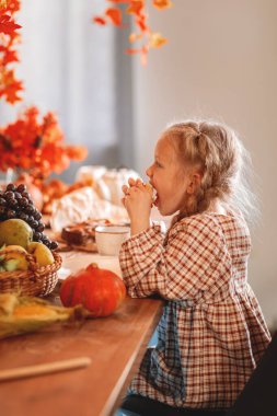 a little girl eating at an autumn table
