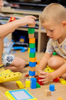 child playing with blocks.  Close-up of children's hands building tall tower with colorful wooden blocks on floor