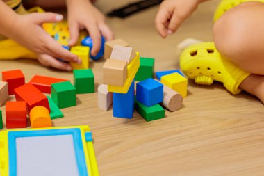 child playing with blocks.  Close-up of children's hands building tall tower with colorful wooden blocks on floor