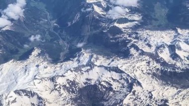 Dünya 'nın üstünde, bulut seviyesinde. Uçan bir uçağın penceresinden manzara gözlendi. Dağlardaki rahatlama ilginç şekiller ortaya çıkarıyor. Köklerimizi kaybettiğimiz için toprak çok uzak ve bizi özlemiş görünüyor. Toprak Ana, seni seviyoruz..