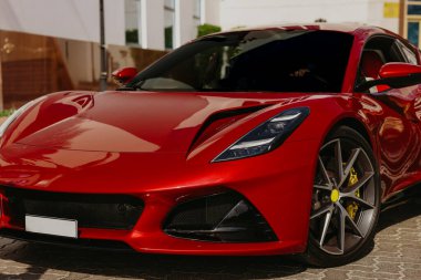 Park yerinde parlak kırmızı spor araba, ön manzara, parlak yüzey.