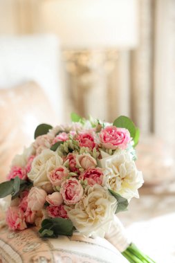 Güllü ve yeşillikli romantik gelin buketi beyaz bir arka planda yatıyor.