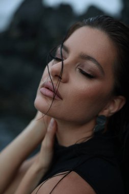 Kayalıklarda poz veren siyah elbiseli güzel bir kadın. 