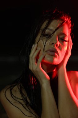 Yağmurun altında, koyu arka planda, yağmurun altında, koyu arkaplanda ıslak saçlı genç bir kadının portresi. Karanlıkta yağmurun altında çekilmiş yakın çekim güzellik modası. 