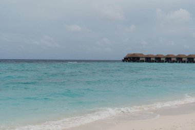 Maldivler 'de turkuaz okyanusu ve açık gökyüzü olan lüks bir deniz aşırı villa. Egzotik tatiller için rüya varış yeri. 