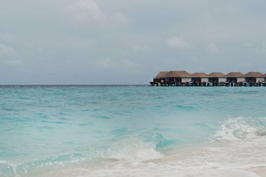 Maldivler 'de turkuaz okyanusu ve açık gökyüzü olan lüks bir deniz aşırı villa. Egzotik tatiller için rüya varış yeri. 