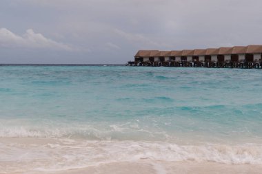 Maldivler 'de turkuaz okyanusu ve açık gökyüzü olan lüks bir deniz aşırı villa. Egzotik tatiller için rüya varış yeri. 