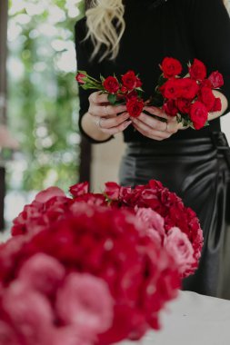 Siyah elbiseli kırmızı gül buketi olan bir kadın. 