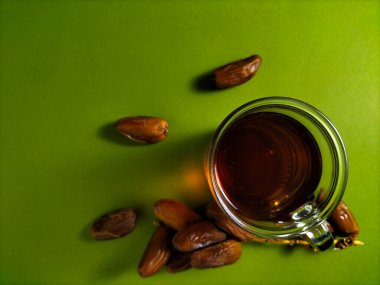a glass of tea with dried dates fruits on green