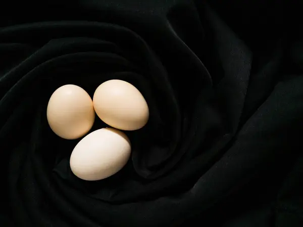 Koyu kumaşın dokusuna yerleştirilmiş yumurtalar.