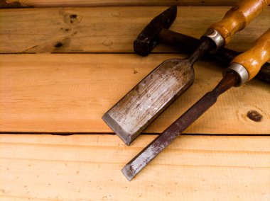 Tahta arka planda çekiç ve keski.