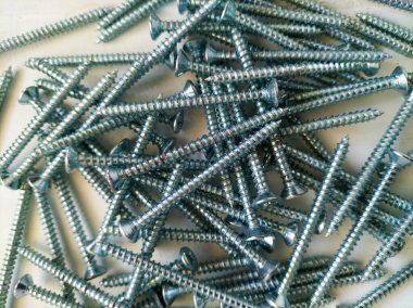 Beyaz yüzeyde gümüş metal vida yığını