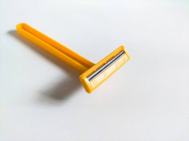 Beyaz arkaplanda sarı tek kullanımlık tıraş bıçağı