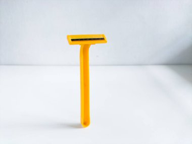 Beyaz arkaplanda sarı tek kullanımlık tıraş bıçağı