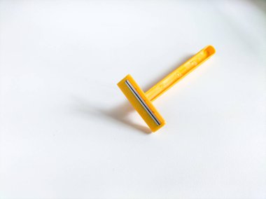 Beyaz arkaplanda sarı tek kullanımlık tıraş bıçağı