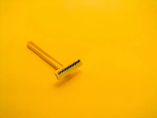 Sarı arka planda tek kullanımlık sarı tıraş bıçağı