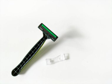 Beyaz arkaplanda yeşil tek kullanımlık tıraş bıçağı