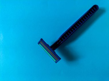 Açık mavi arkaplanda tek kullanımlık mavi jilet