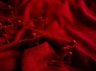 Kırmızı kumaş üzerinde küçük kırmızı plastik oyuncak askerler koleksiyonu.