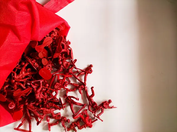 Kırmızı çantada küçük kırmızı plastik oyuncak askerler koleksiyonu.