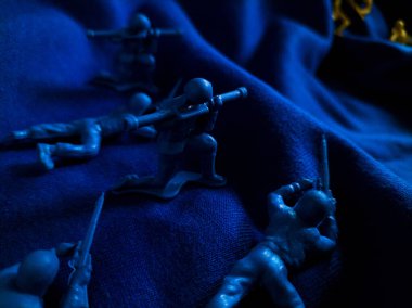 Mavi kumaş üzerinde küçük mavi plastik oyuncak askerler koleksiyonu.