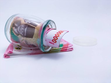 Cam bir kavanozda yuvarlanmış Endonezya rupiası banknotu var.