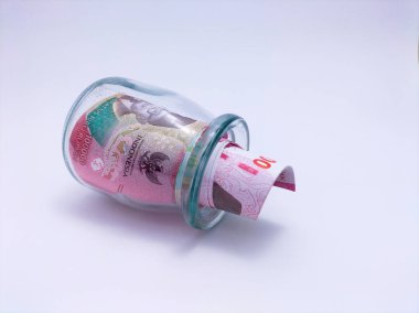 Cam bir kavanozda yuvarlanmış Endonezya rupiası banknotu var.