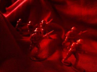 Kırmızı kumaş arka planda kırmızı plastik ordu oyuncağı