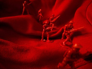 Kırmızı kumaş arka planda kırmızı plastik ordu oyuncağı