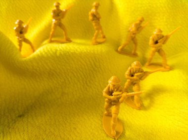 Sarı kumaş arka planda sarı plastik ordu oyuncağı