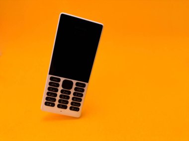 Parlak turuncu bir arkaplana karşı eski bir cep telefonu