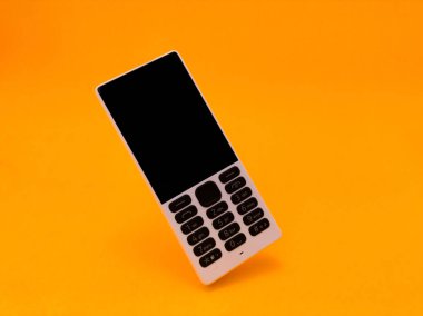 Parlak turuncu bir arkaplana karşı eski bir cep telefonu