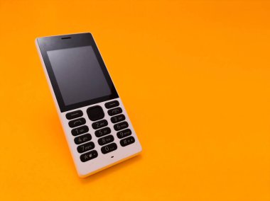 Parlak turuncu bir arkaplana karşı eski bir cep telefonu