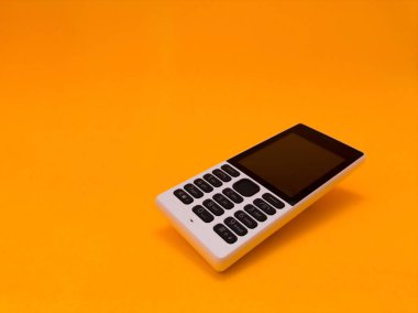 Parlak turuncu bir arkaplana karşı eski bir cep telefonu
