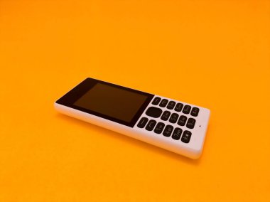 Parlak turuncu bir arkaplana karşı eski bir cep telefonu
