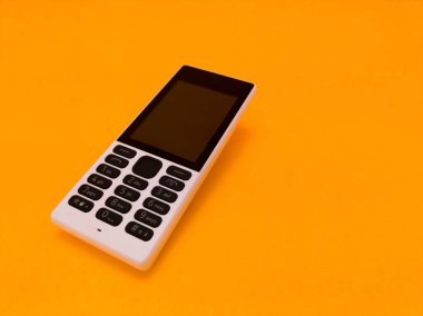 Parlak turuncu bir arkaplana karşı eski bir cep telefonu