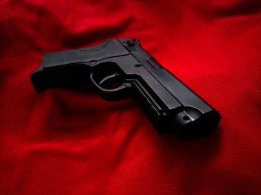 Kırmızı desenli kumaşta oyuncak silah.